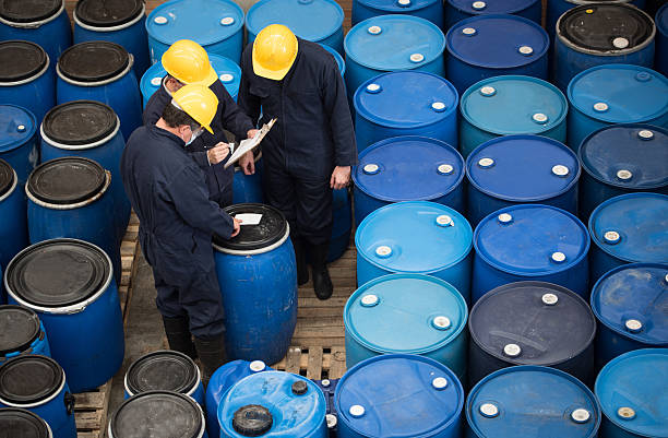 Group of men working at a chemical warehouse classifying barrels