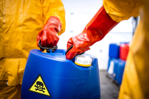 Close up view of plastic canister with toxic material carried by workers in protection suit.